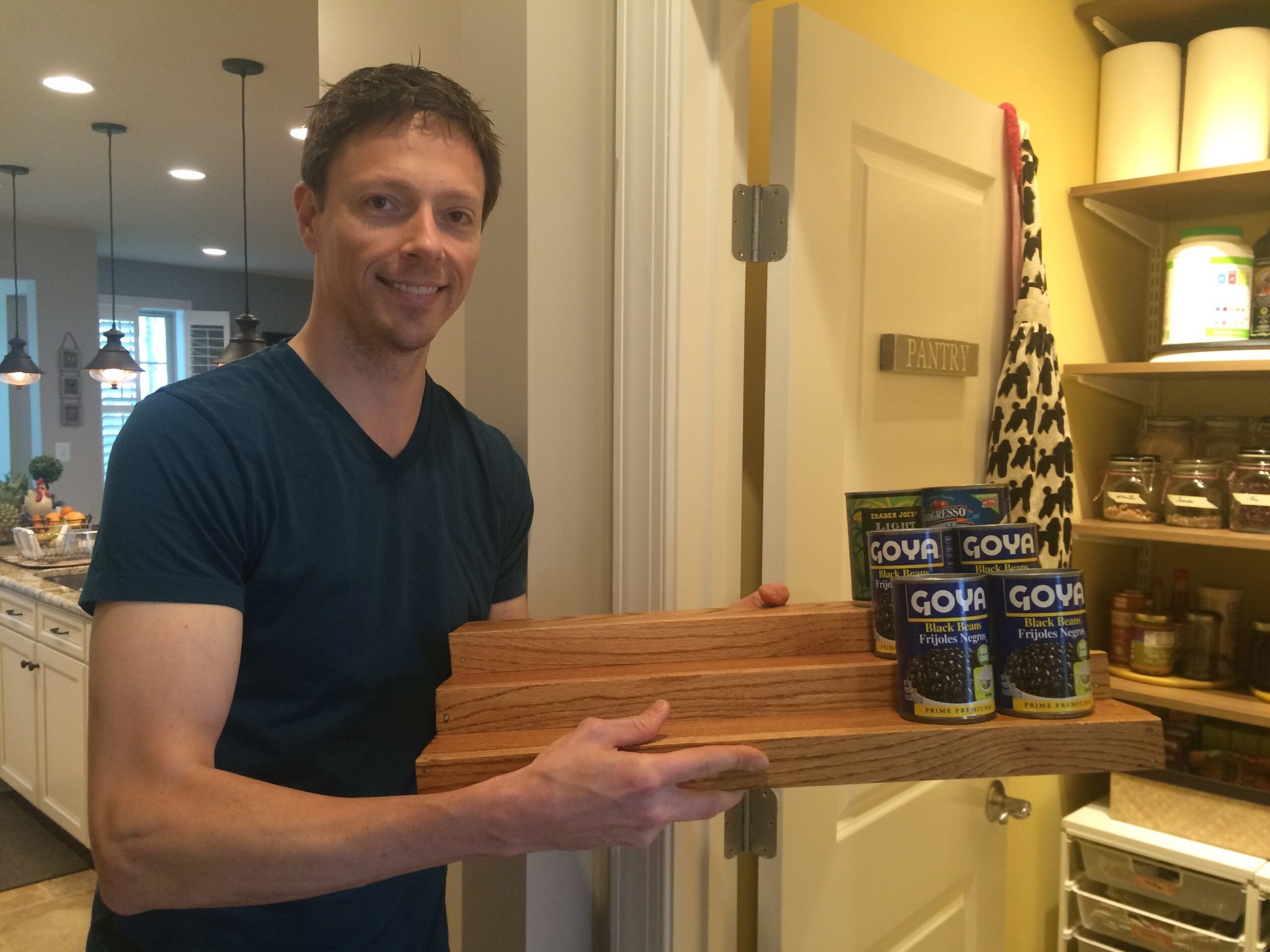 Ed proudly displaying the wooden tiered shelf he just finished making for the pantry!